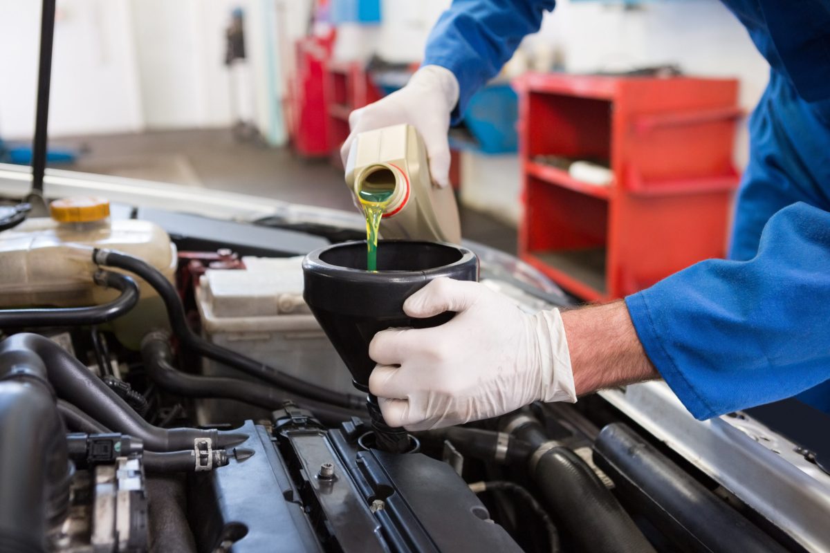 Mechanic pouring oil into car at the repair garage